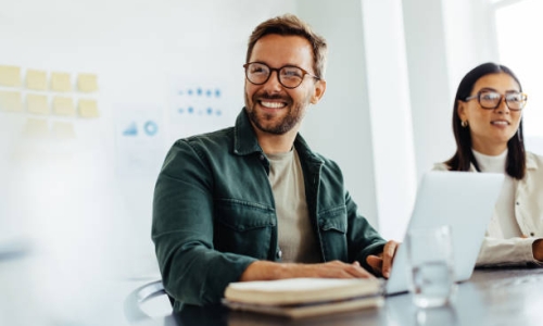 Happy business man listening to a discussion in an office boardroom. Business professional sitting in a meeting with his colleagues.